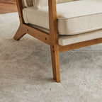 Poltrona imbottita in misto lino con gambe in legno e un cuscino beige